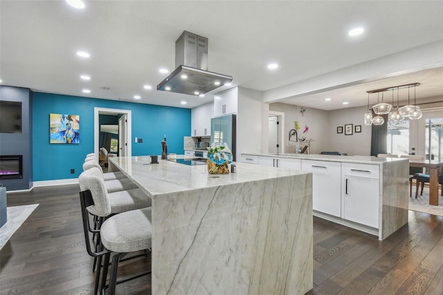 kitchen featuring island range hood, white cabinets, stainless steel refrigerator, hanging light fixtures, and a large island