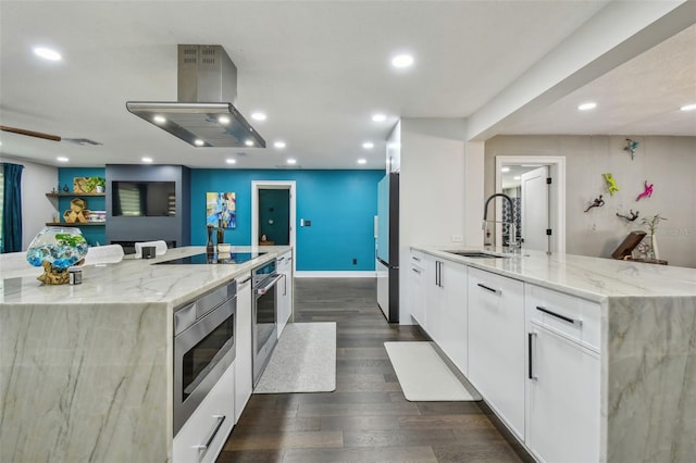 kitchen with a large island with sink, stainless steel appliances, white cabinetry, and sink