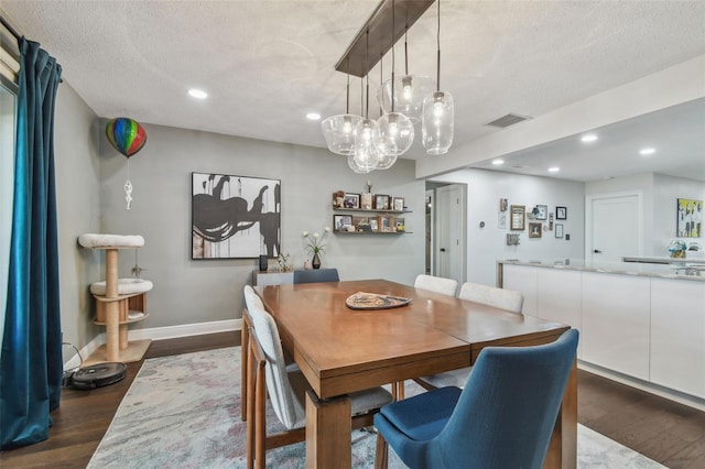 dining room featuring a textured ceiling and dark hardwood / wood-style floors