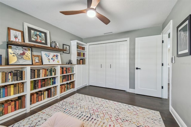 living area with a textured ceiling, ceiling fan, and dark wood-type flooring