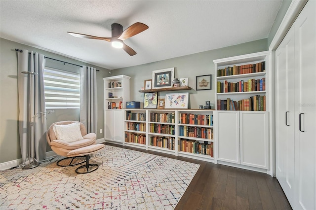 sitting room featuring ceiling fan, dark hardwood / wood-style floors, and a textured ceiling