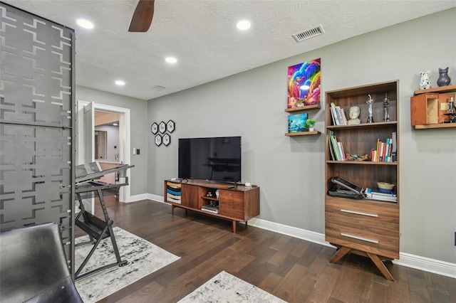 living room with a textured ceiling, dark hardwood / wood-style flooring, and ceiling fan