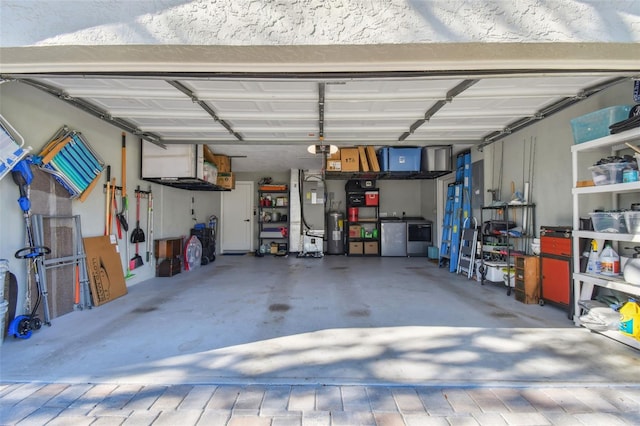 garage with refrigerator, electric water heater, and separate washer and dryer