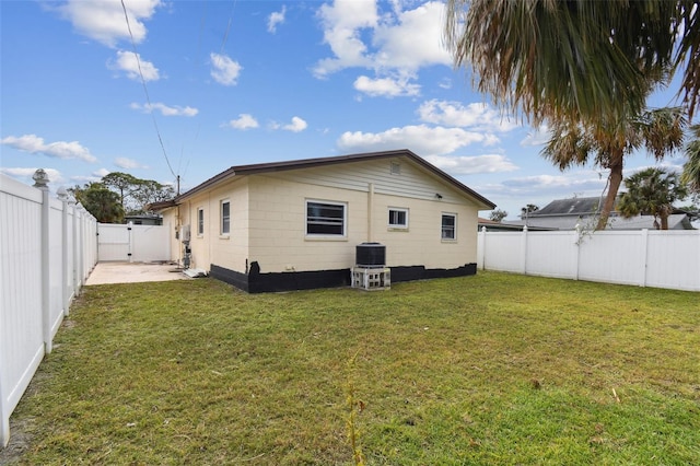 back of house with central AC unit and a yard