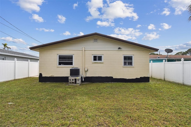 back of house featuring a lawn and central air condition unit