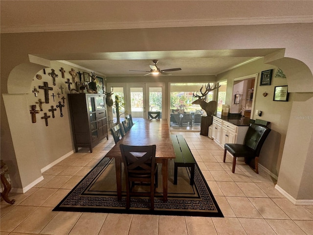 dining area featuring ceiling fan, crown molding, and light tile patterned flooring