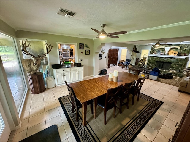 tiled dining room featuring a fireplace, ceiling fan, and a textured ceiling