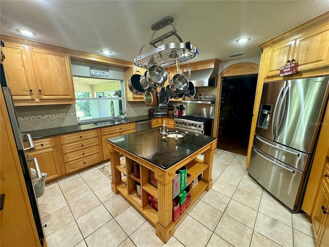 kitchen with sink, wall chimney exhaust hood, decorative backsplash, light tile patterned floors, and appliances with stainless steel finishes