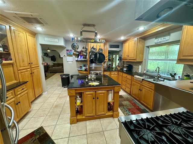 kitchen with decorative backsplash, gas stove, sink, a center island, and light tile patterned flooring