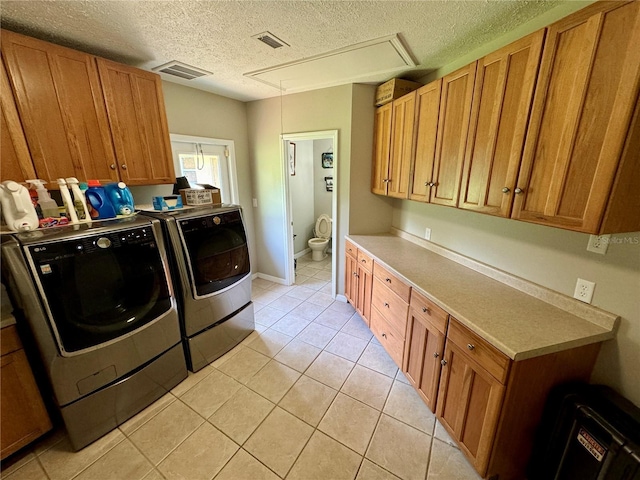 laundry area with light tile patterned floors, cabinets, a textured ceiling, and independent washer and dryer