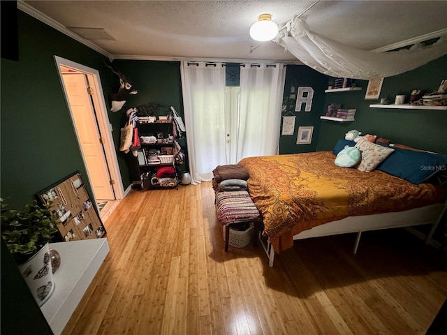 bedroom featuring hardwood / wood-style floors, crown molding, and a textured ceiling