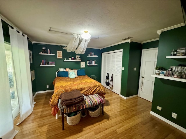 bedroom with a textured ceiling, hardwood / wood-style flooring, a closet, and ornamental molding