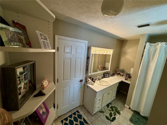 bathroom with tile patterned flooring, vanity, and a textured ceiling