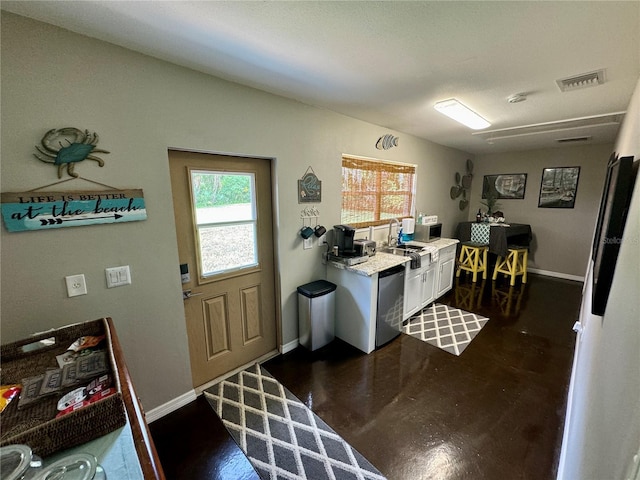 kitchen with dishwasher, white cabinetry, and light stone countertops