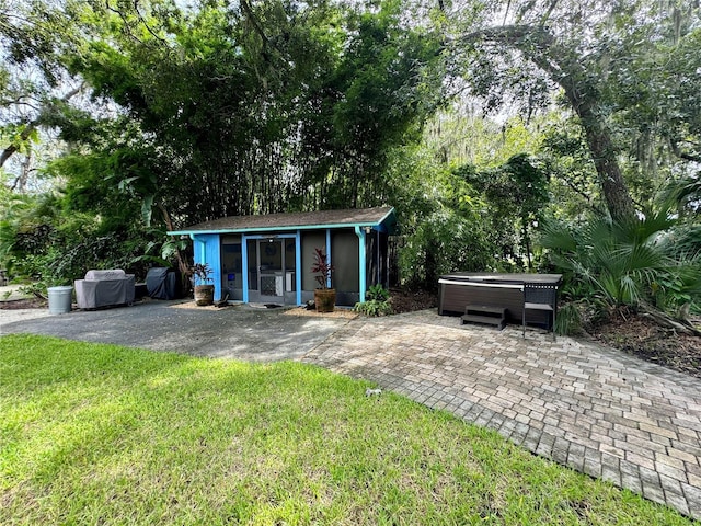 view of outdoor structure with a lawn and a hot tub