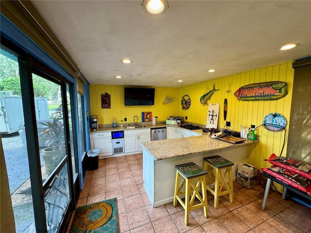 kitchen with white cabinets, a kitchen breakfast bar, sink, stainless steel dishwasher, and kitchen peninsula