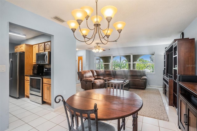 tiled dining area featuring a textured ceiling and ceiling fan with notable chandelier