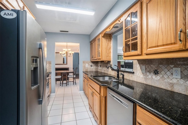 kitchen featuring appliances with stainless steel finishes, sink, light tile patterned floors, decorative light fixtures, and an inviting chandelier