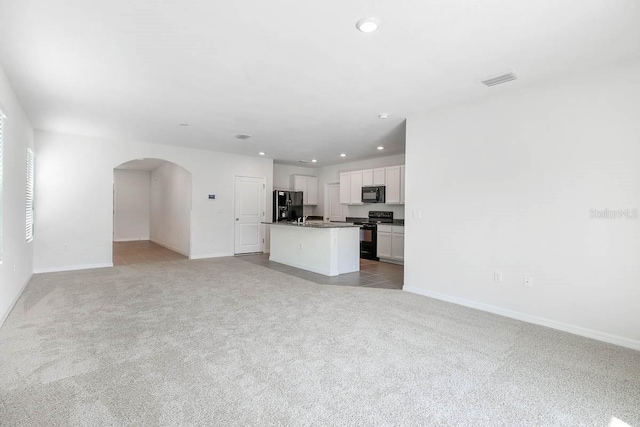 unfurnished living room featuring light carpet and sink