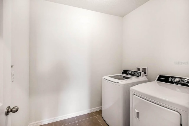 laundry room with washer and dryer and dark tile patterned floors