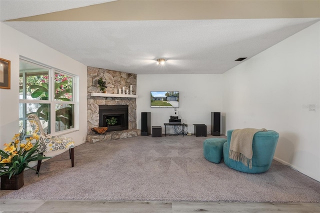 living room with a textured ceiling, a fireplace, and carpet