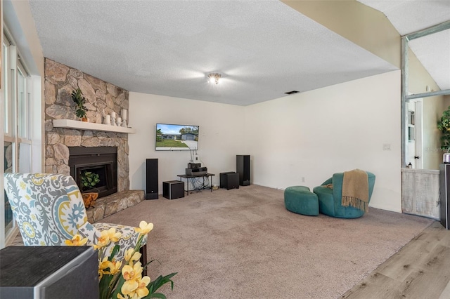 living room with a stone fireplace, a textured ceiling, and hardwood / wood-style flooring