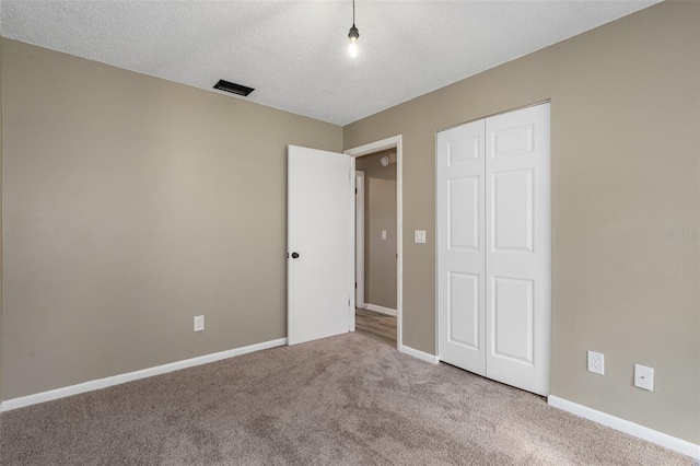 unfurnished bedroom featuring a closet, light colored carpet, and a textured ceiling