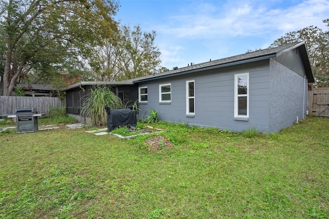 back of property with a lawn and a sunroom