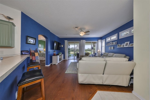 living room featuring ceiling fan, wood-type flooring, and a textured ceiling