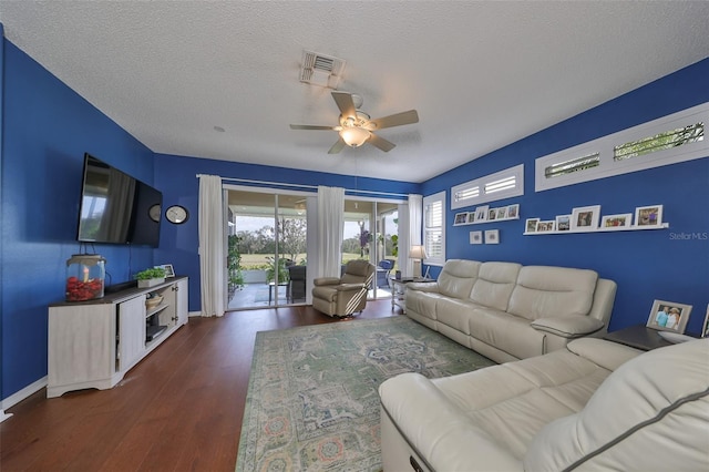 living room with ceiling fan, dark hardwood / wood-style flooring, and a textured ceiling