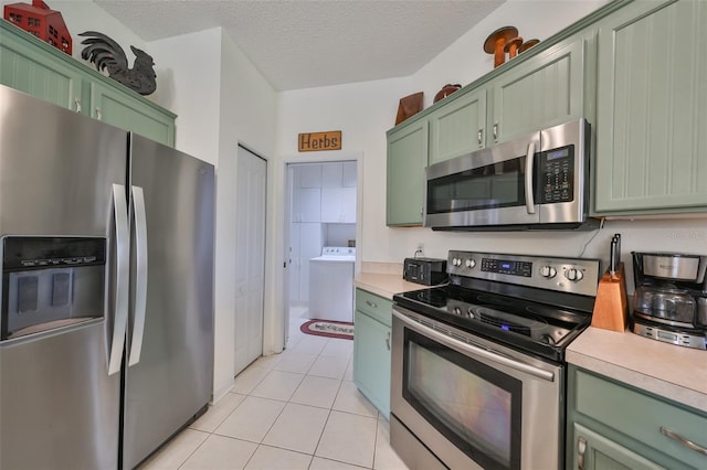 kitchen featuring washer / clothes dryer, green cabinets, a textured ceiling, and appliances with stainless steel finishes