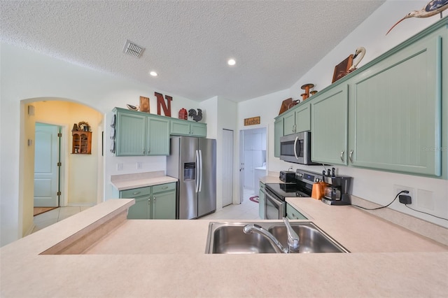 kitchen with sink, a textured ceiling, appliances with stainless steel finishes, and green cabinetry