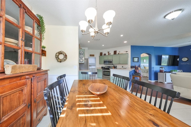 tiled dining room featuring a textured ceiling and an inviting chandelier