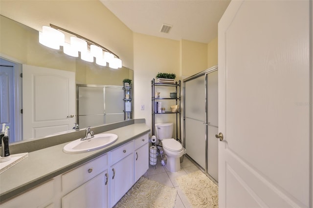 bathroom with tile patterned floors, vanity, toilet, and a shower with door