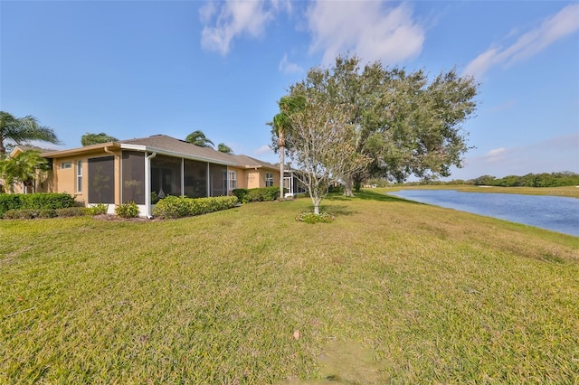 view of yard with a sunroom and a water view