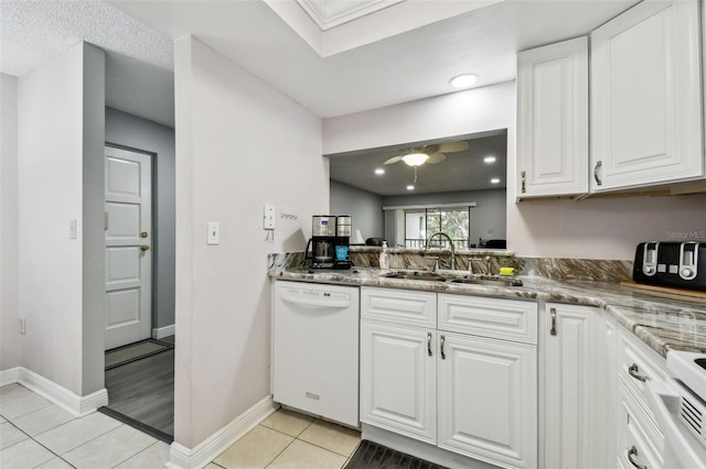 kitchen featuring white dishwasher, white cabinets, sink, stone countertops, and light tile patterned flooring