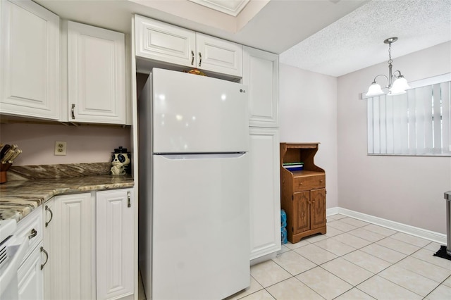 kitchen with white fridge, white cabinetry, dark stone counters, and an inviting chandelier