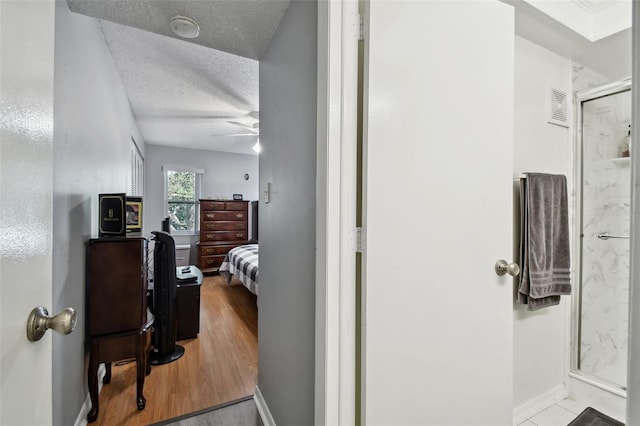 bathroom featuring a textured ceiling, hardwood / wood-style flooring, an enclosed shower, and ceiling fan