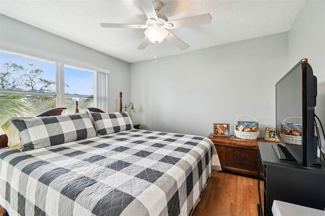 bedroom featuring a textured ceiling, dark hardwood / wood-style floors, and ceiling fan