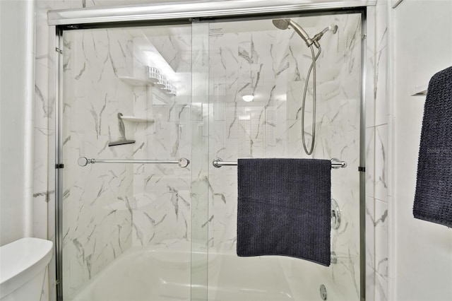 bathroom with bath / shower combo with glass door and toilet