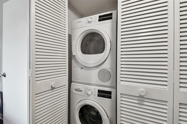 washroom featuring a textured ceiling and stacked washer and clothes dryer