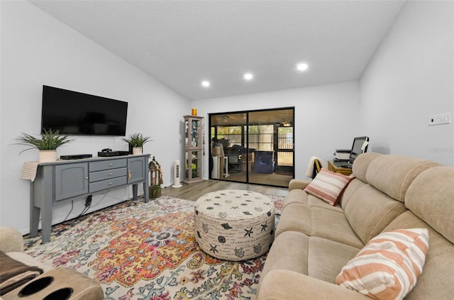 living room featuring a textured ceiling, light wood-type flooring, and lofted ceiling