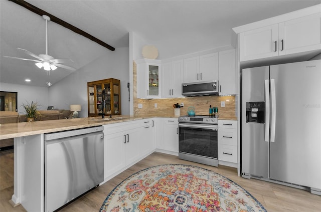 kitchen featuring kitchen peninsula, backsplash, stainless steel appliances, vaulted ceiling with beams, and white cabinetry