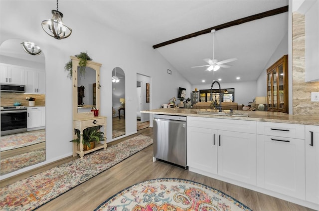 kitchen featuring appliances with stainless steel finishes, backsplash, ceiling fan with notable chandelier, vaulted ceiling with beams, and white cabinetry