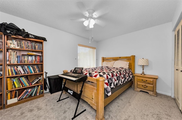 bedroom featuring ceiling fan, a closet, light carpet, and a textured ceiling