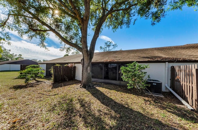 back of house with a yard and central AC