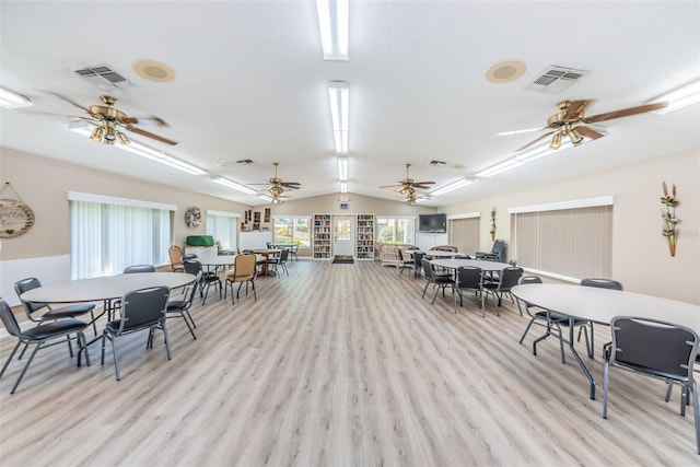 dining space with ceiling fan, light wood-type flooring, and vaulted ceiling