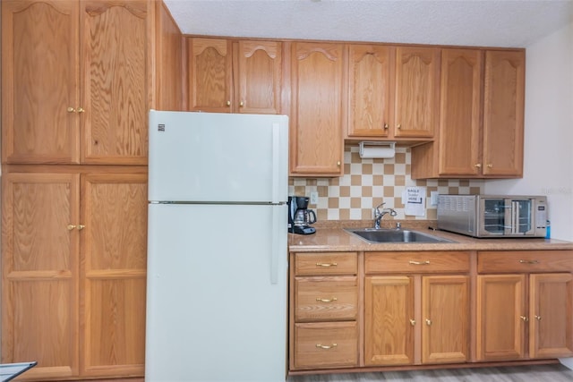 kitchen with decorative backsplash, a textured ceiling, white refrigerator, and sink