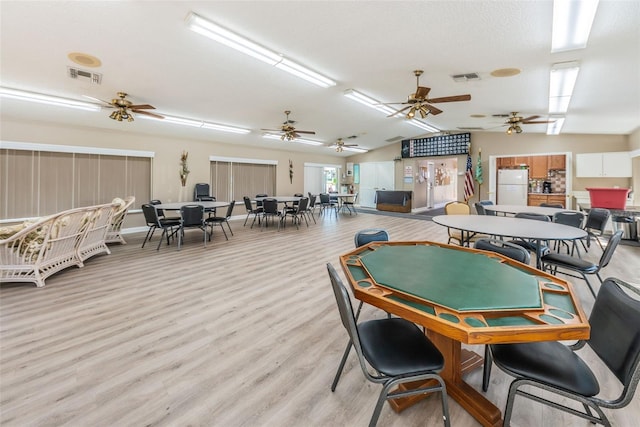 recreation room featuring ceiling fan, light wood-type flooring, a textured ceiling, and vaulted ceiling