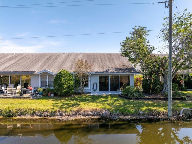 back of house featuring a water view and a yard